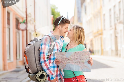 Image of smiling couple with map and backpack in city