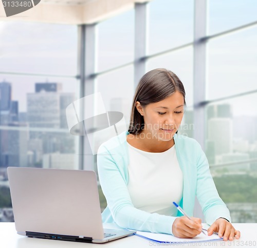 Image of smiling woman with laptop and notebook