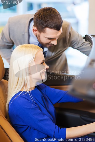 Image of happy couple buying car in auto show or salon