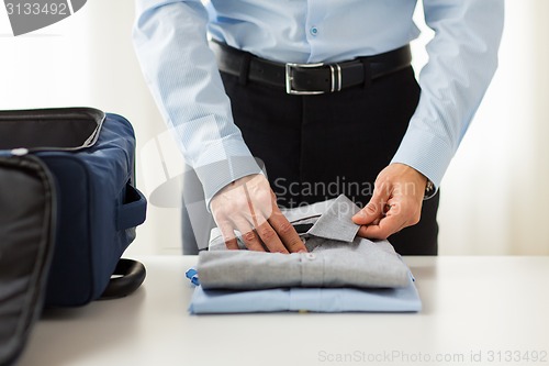 Image of businessman packing clothes into travel bag