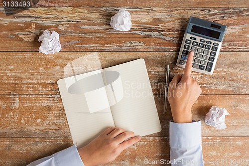 Image of close up of hands with calculator and notebook