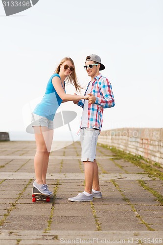 Image of smiling couple with skateboard outdoors