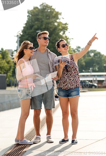 Image of smiling friends with map and city guide outdoors