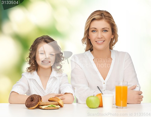 Image of happy mother and daughter eating breakfast