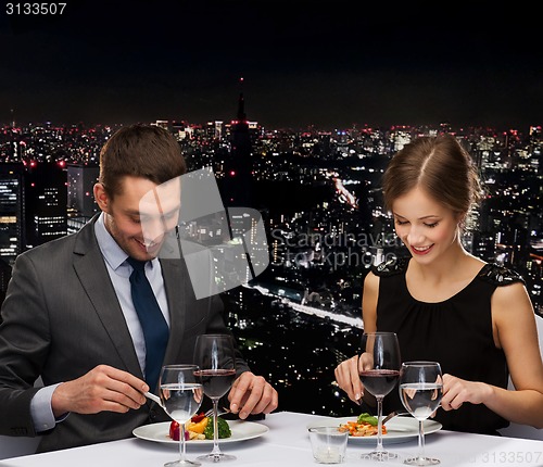 Image of smiling couple eating main course at restaurant