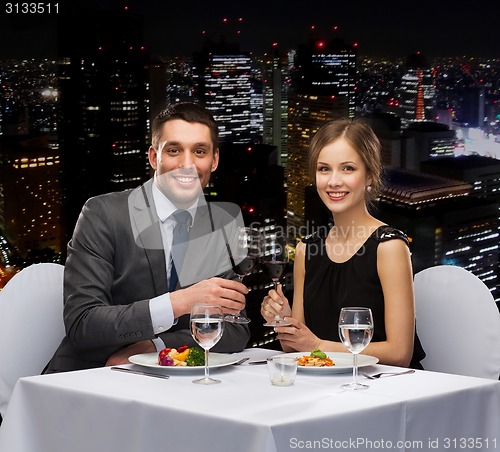 Image of smiling couple eating main course at restaurant