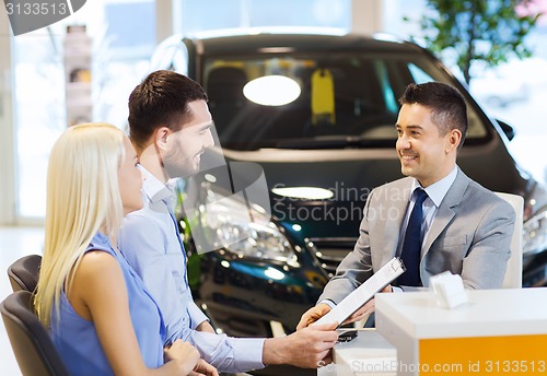 Image of happy couple with car dealer in auto show or salon