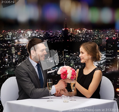 Image of smiling man giving flower bouquet to woman