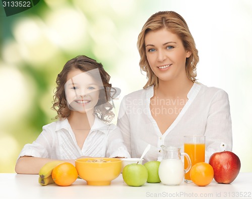 Image of happy mother and daughter eating breakfast