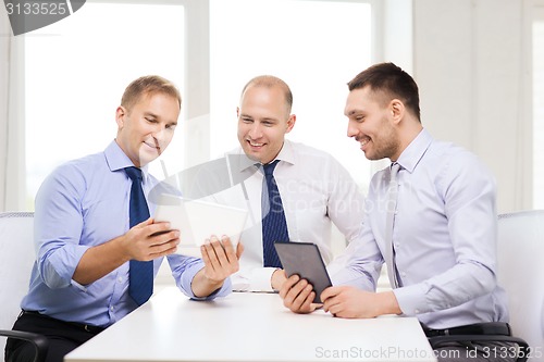 Image of three smiling businessmen with tablet pc in office