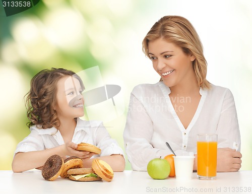 Image of happy mother and daughter eating breakfast