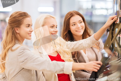 Image of happy young women choosing clothes in mall