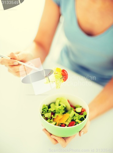 Image of woman eating salad with vegetables