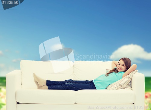 Image of smiling little girl lying on sofa