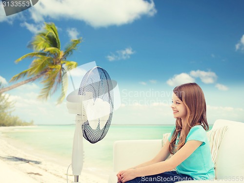 Image of smiling little girl with big fan at home