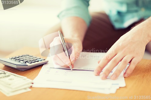 Image of close up of man counting money and making notes