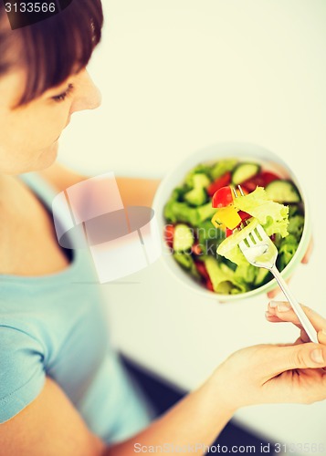 Image of woman eating salad with vegetables