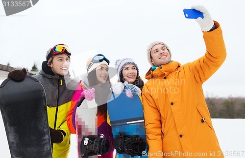 Image of happy friends with snowboards and smartphone