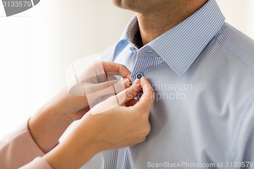 Image of close up of man and woman fastening shirt buttons