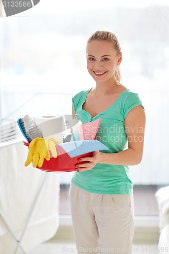 Image of happy woman holding cleaning stuff at home