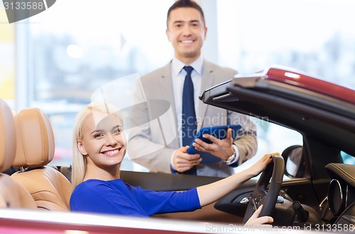 Image of happy woman with car dealer in auto show or salon