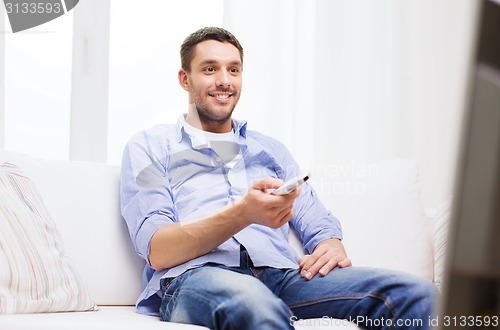 Image of smiling man with tv remote control at home