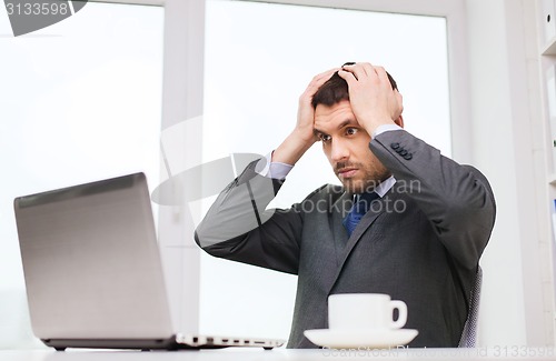 Image of businessman with laptop typing in office