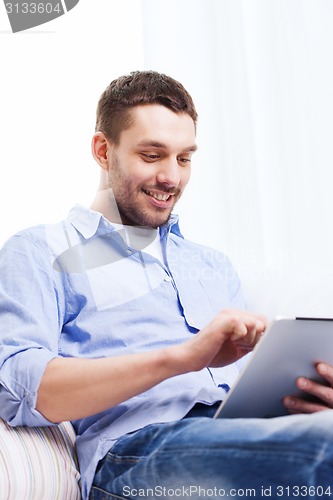 Image of smiling man with tablet pc and cup at home