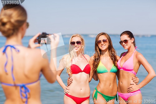 Image of group of smiling women photographing on beach