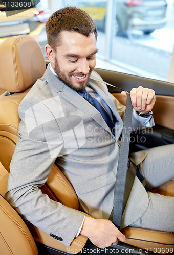 Image of happy man sitting in car at auto show or salon