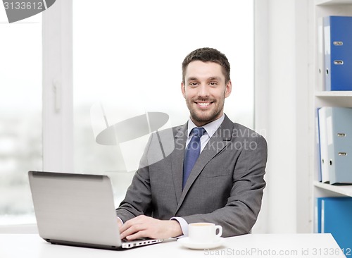 Image of smiling businessman with laptop and coffee