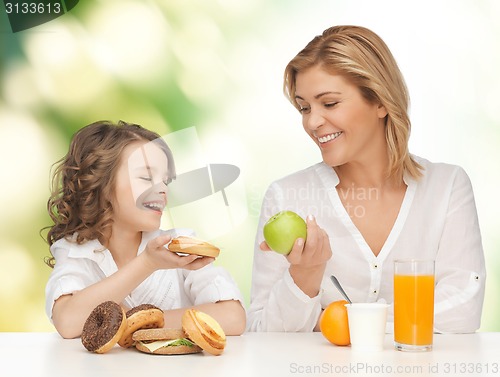 Image of happy mother and daughter eating breakfast