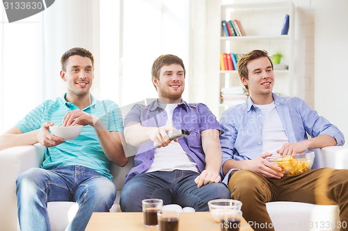 Image of happy male friends watching tv at home