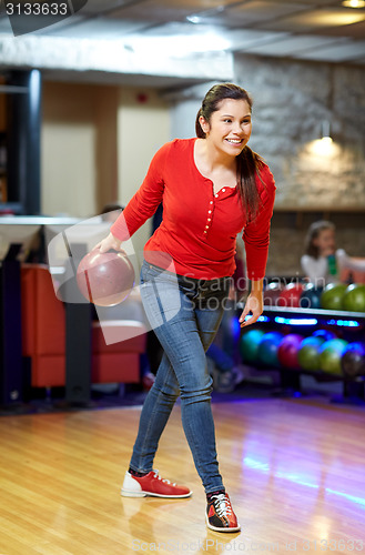 Image of happy young woman throwing ball in bowling club