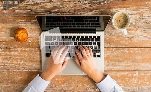 Image of close up of female hands with laptop and coffee