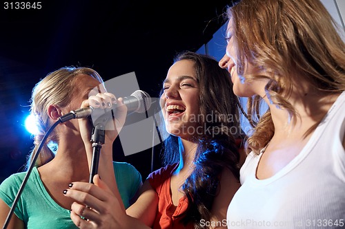 Image of happy young women singing karaoke in night club