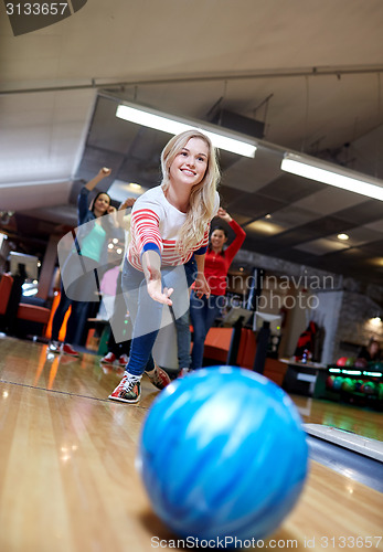 Image of happy young woman throwing ball in bowling club