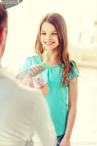 Image of male doctor giving toothbrush to smiling girl