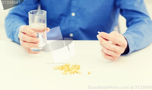 Image of male hand holding pill and glass of water