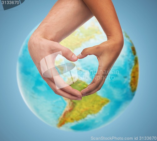 Image of human hands showing heart shape over earth globe