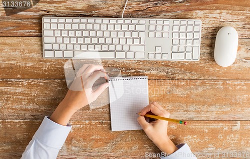 Image of close up of hands with notebook and keyboard