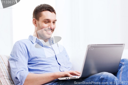 Image of smiling man working with laptop at home