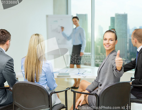 Image of businesswoman with team showing thumbs up