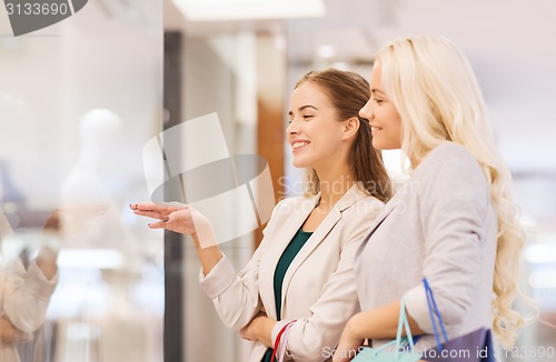 Image of happy young women with shopping bags in mall