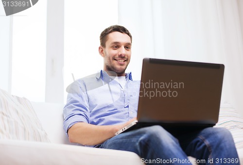 Image of smiling man working with laptop at home