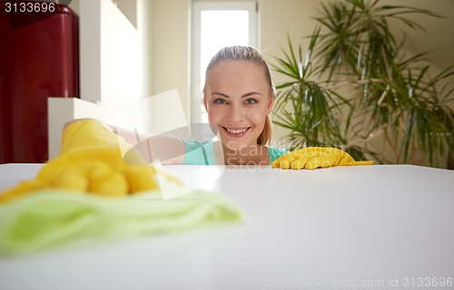 Image of happy woman cleaning table at home kitchen