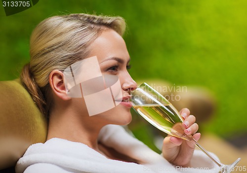 Image of beautiful young woman drinking champagne at spa