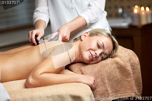 Image of close up of woman having hot stone massage in spa