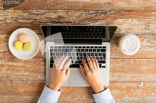 Image of close up of female hands with laptop and coffee