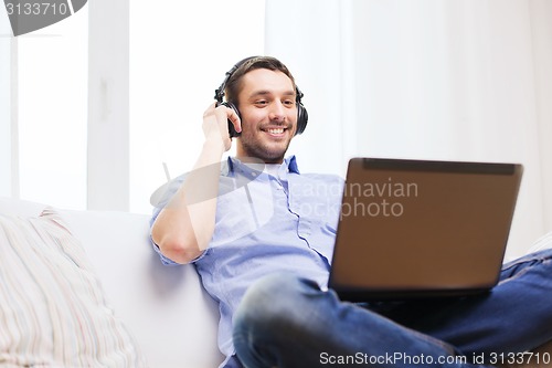 Image of smiling man with laptop and headphones at home